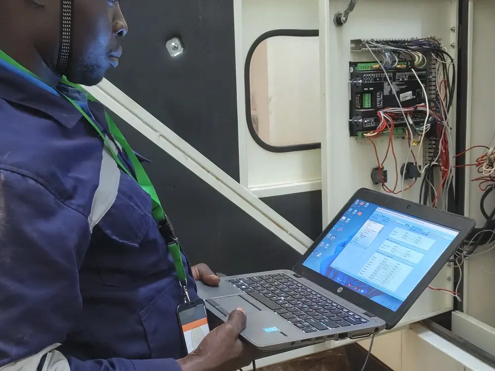 Engineer diagnosing a generator controller fault with a laptop