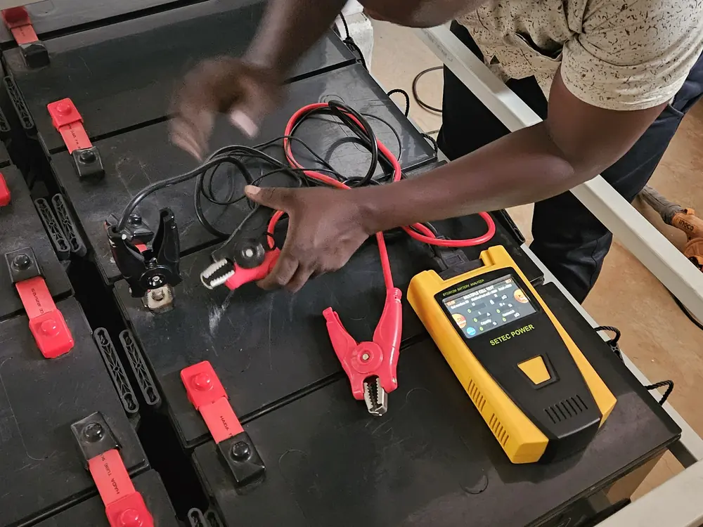 Technician testing UPS battery terminals during maintenance